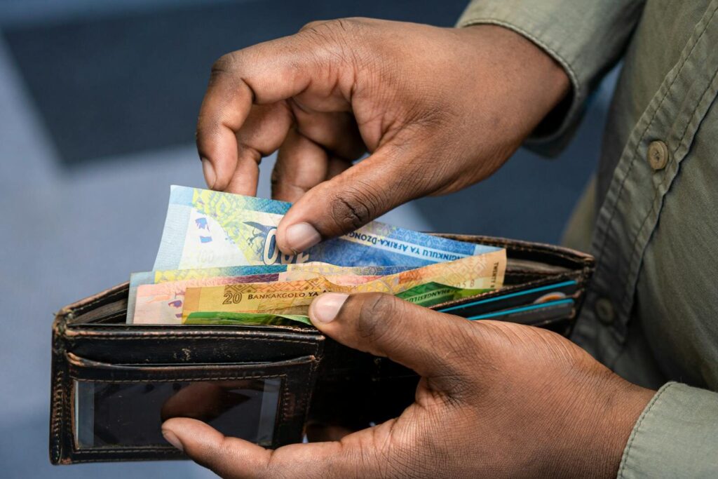 A person counting South African Rand from a wallet, symbolizing money saved from off-grid power system.